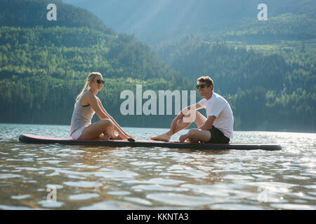 Couple enjoying stand up paddleboarding in river Stock Photo