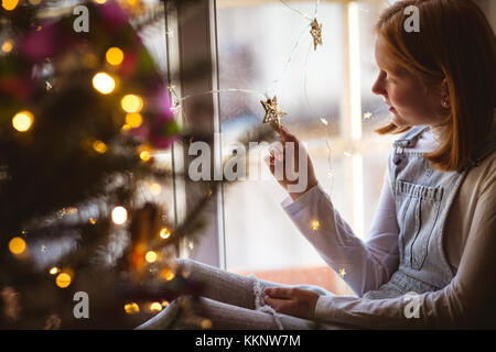 Girl sitting on window sill and looking at star shape Stock Photo