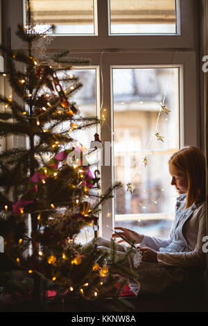Girl sitting near window and using digital tablet at home Stock Photo