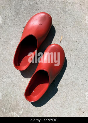 Red rubber clogs on patio. Stock Photo