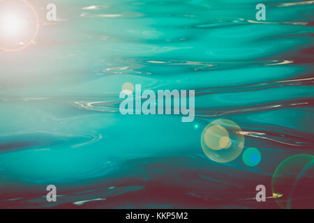 Background image of water in a tropical swimming pool with copy-space and lens flare- Stock Photo