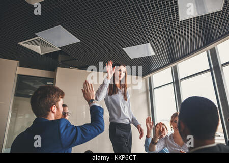 business team giving a high fives gesture as they laugh and cheer their success Stock Photo