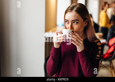 Young girl sit with cup of coffee and smile to the camera Stock Photo