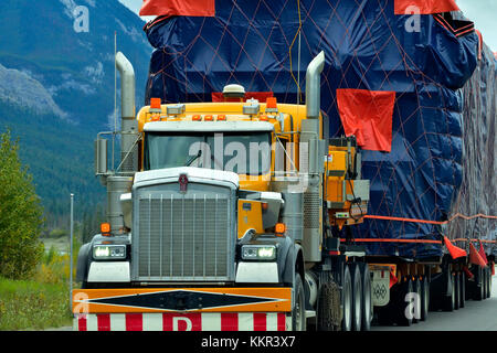 A close up of a semi truck with an oversize load traveling on an Alberta highway Stock Photo