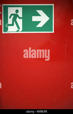 Sign Emergency exit / escape route on a red wall, Stock Photo