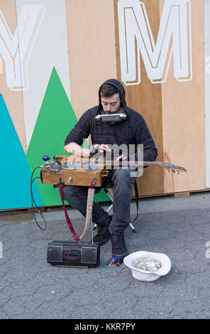 A one man band musician playing a homemade instrument for donations outside the Union Square Holiday Market in New York Stock Photo