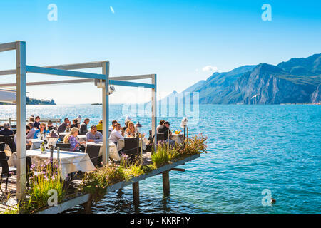 Malcesine, lake Garda, Verona province, Veneto, Italy. Tourists eating out in a restaurant on water. Stock Photo