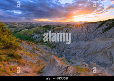 Sun filters through the clouds during sunset illuminating the Calanchi of Atri, Abruzzo, Italy. Stock Photo