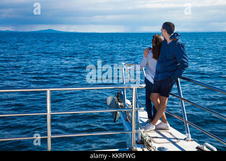 A couple embracing each other, looking out to sea on a cruise boat (Whale and Dolphin Safari, Auckland, New Zealand) Stock Photo