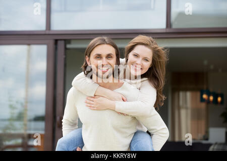 Man holding woman on back outdoors, looking at camera, portrait Stock Photo