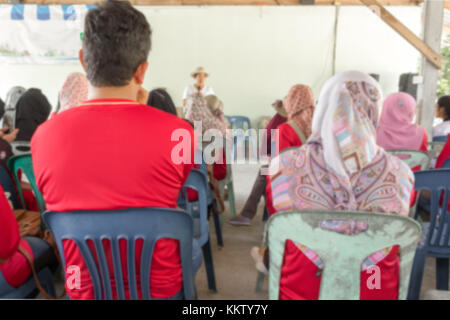 Blurred abstract background of university students sitting in a lecture room with teacher of the out Community education: Blurry view from back of the Stock Photo