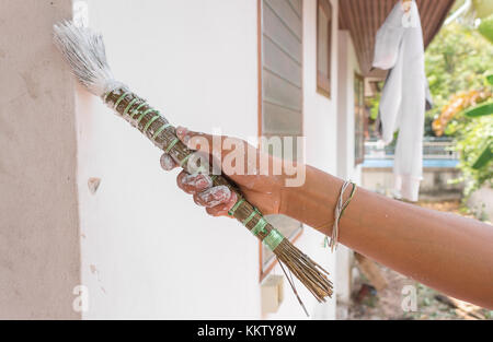 Painting walls.Painter paints using a brush,hand worker holding brush painting white on cement wall. (select focus hand ) Stock Photo