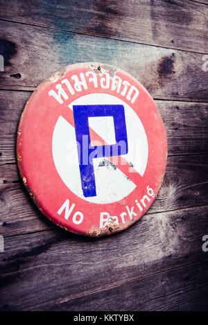 Rusty steel no parking sign in Thai language attached on classic wooden wall Stock Photo