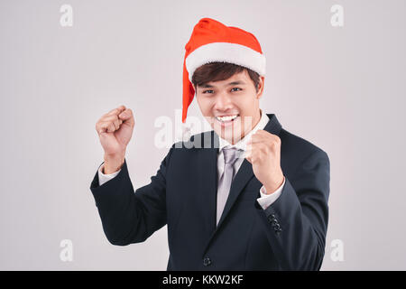 Excited businessman in black suit and santa hat isoalted on white Stock Photo