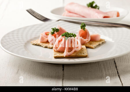 photo of cracker appetizer with  ham and parsley on white wooden table Stock Photo