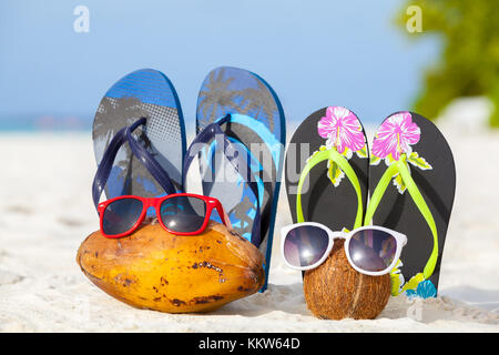 Maldives, coconuts with sunglasses and bathing shoes on the beach Stock Photo