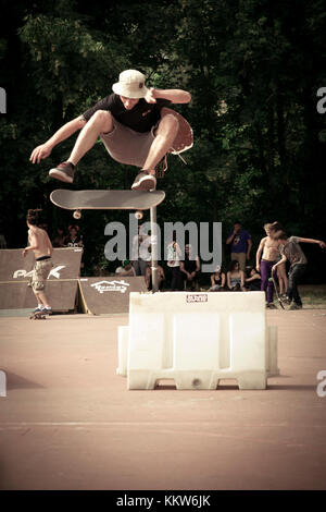 a guy jumps a hurdle with the skateboard----Savona, SV, Liguria, Italy - July 21, 2014: A young boy jumping on the skateboard in a skatepark during a  Stock Photo
