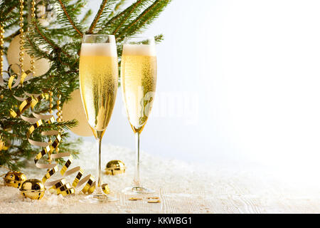 Two glasses of champagne ready to bring New Year on Christmas tree background Stock Photo