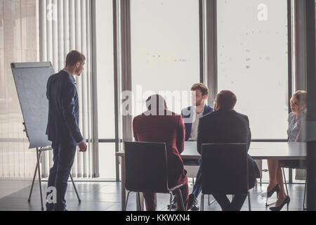 Business plan explained on flipchart by CEO to colleagues Stock Photo