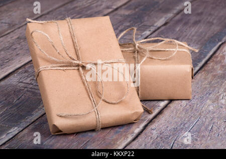 Gifts wrapped in brown paper on a wood textured surface Stock Photo
