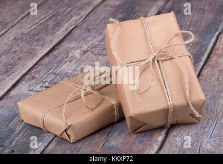 Gifts wrapped in brown paper on a wood textured surface Stock Photo