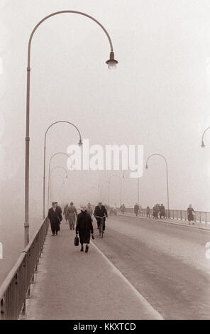 This black-and-white photograph shows a foggy scene on the old bridge in Maribor, Slovenia, from 1961. The image captures the historical and atmospheric elements of the city during that era. Stock Photo