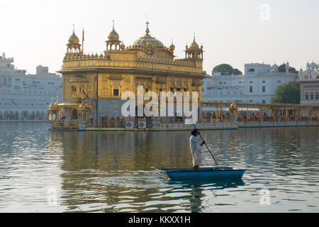 Punjabi Sikh man guides punt over man made pool at Golden temple in Amritsar, Punjab Stock Photo