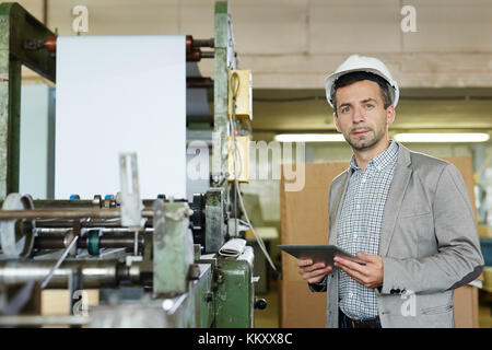 Engineer in hardhat browsing in the net and looking for technical data Stock Photo
