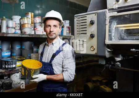Technical repairman with bucket of yellow paint in storage room Stock Photo