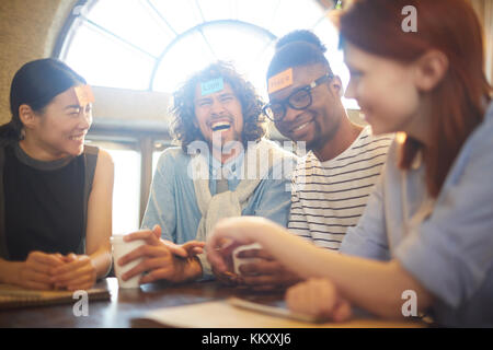 Young friends or colleagues playing name game in cafe at leisure or break Stock Photo