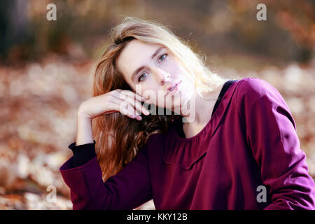 Young woman in beautiful autumn park, concept autumn. Closeup of young blond girl, looking at camera. Stock Photo