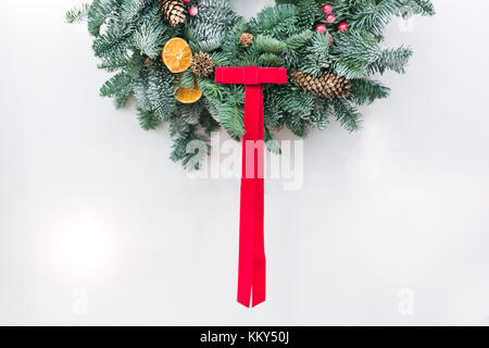culture, religion, decor concept. on the snowy white background there is half of the wreath decorated with dried citrus fruits, red berries and pineco Stock Photo