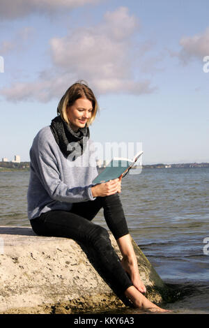 Woman, blond, Baltic Sea, leisure time, sitting on beach, reading a book, Stock Photo