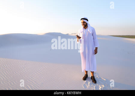 Arab young sheikh calls to friend or business partner and with smile on face and joy in eyes tells about winnings and amount of money in hands, rejoic Stock Photo