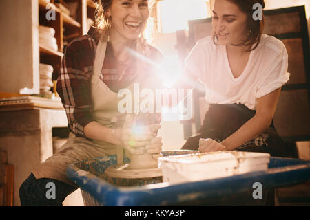Woman potter teaching the art of pot making. Woman working on potters wheel making clay objects. Stock Photo
