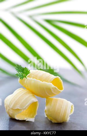 three Butter curl or roll, front view.greenery in the background Stock Photo
