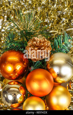 Orange baubles, golden tinsel and artificial fir tree branch as decoration for Christmas Stock Photo