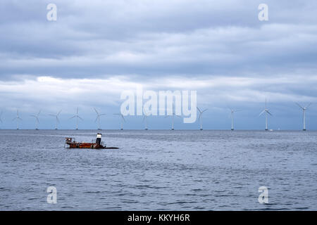 Sunken shipwreck with only the top sticking out of the water, with a row of windmills in the background, near Amager Strandpark in Denmark Stock Photo