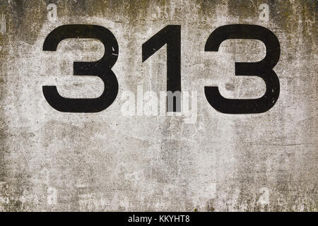 A concrete wall with the number 313 written on it. Stock Photo
