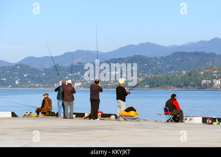 Batumi, Georgia, 11-04-2017: Fishermen in the port on the background of the mountains fishing. Stock Photo