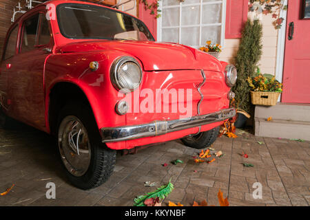 Retro red car on autumn scenery in front of the house Stock Photo