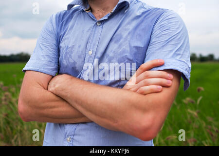 Man with hyperhidrosis sweating very badly under armpit in blue shirt, isolated on grey Stock Photo