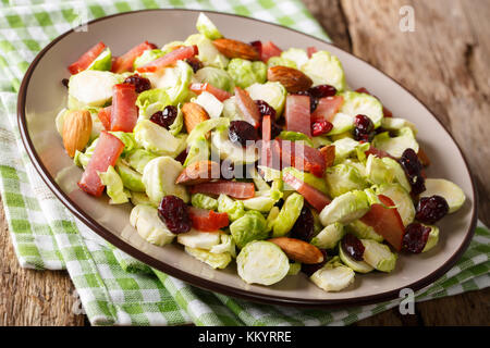 Homemade salad of sliced Brussels sprouts, cranberries, almonds and ham close-up on a plate on a table. horizontal