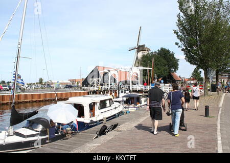 Tourists strolling  along Vissershaven (Fishing Port, nowadays recreational harbour), Harderwijk, The Netherlands. In background corn mill De Hoop. Stock Photo