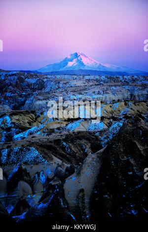 Snow covered volcanic 3916m peak of Mount Erciyes, highest mountain in central Anatolia Turkey. S.E. over gorges of Goreme. Dusk Stock Photo