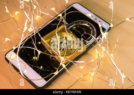 Bitcoin and padlock over a screen with a web of connected dot lights on the foreground Stock Photo