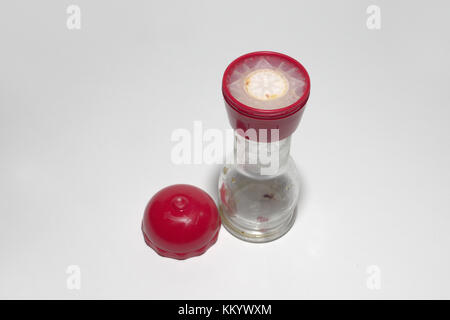 Manual adjustable pepper mill of glass and plastic with red cap. Empty Stock Photo