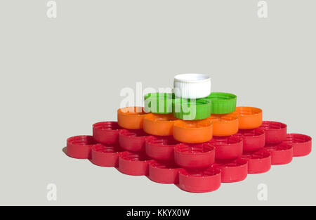 whites, reds, greens, oranges striped caps from plastic bottles are collected in pyramid Stock Photo
