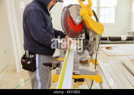 Contractor Using Circular Saw Cutting New Crown Moulding for Renovation. Stock Photo