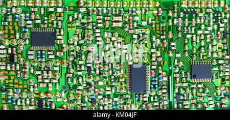 Impressive printed circuit board with many electronic parts. Varied electrotechnical background with surface mount of components in green shade. Stock Photo